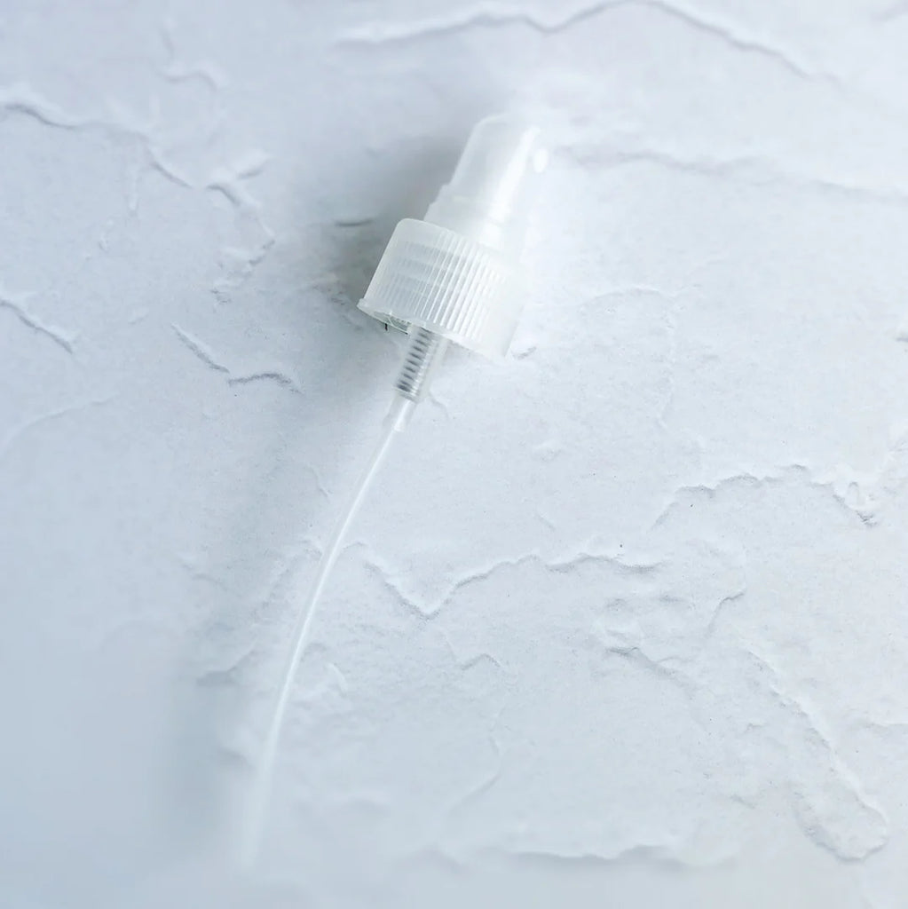Plastic spray bottle nozzle on textured white surface.