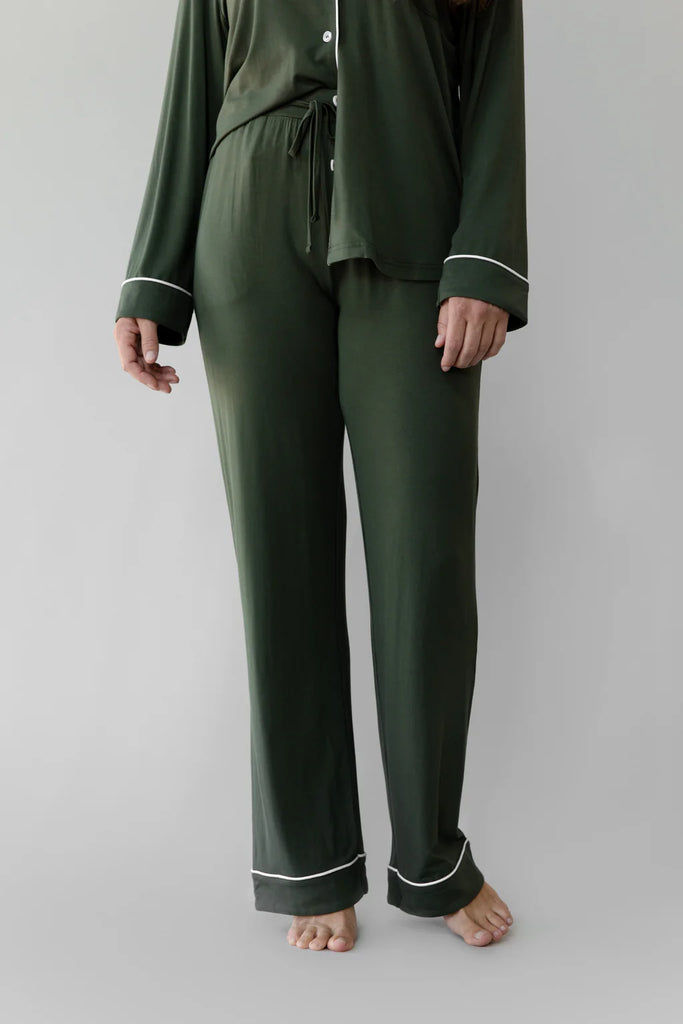 A person wearing Cozy Earth Women's Stretch-Knit Bamboo Pajama Pant in Olive with white trim, standing barefoot, facing forward. Hands are visible at sides, and the top is partially tucked in. These women's bamboo pajamas offer enhanced breathability and temperature regulation for a comfortable night's sleep.