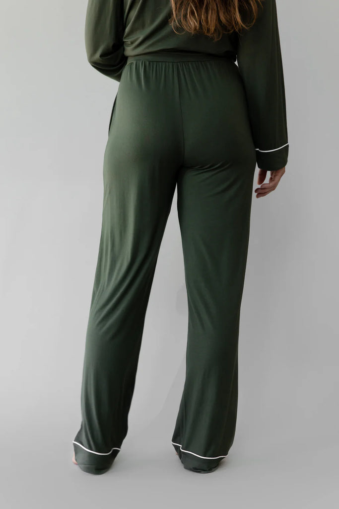 A person wearing Cozy Earth Women's Stretch-Knit Bamboo Pajama Pants in Olive, featuring enhanced breathability and white trim, is standing with their back to the camera against a neutral background.