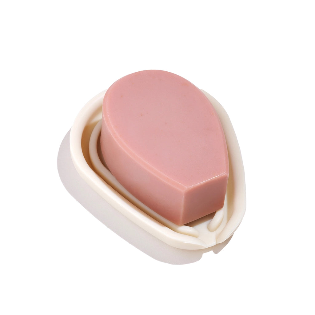 A bar of pink soap on a white soap dish against an isolated background.