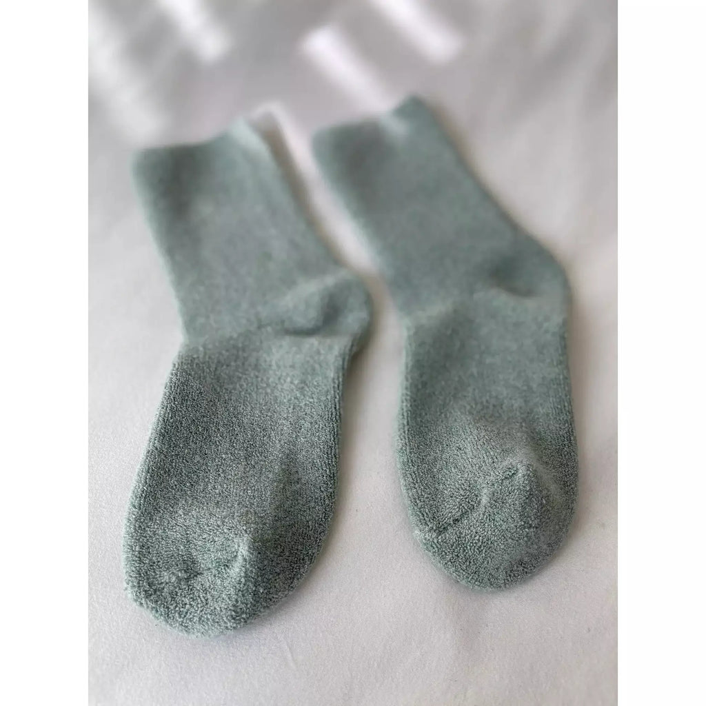 A pair of light green socks laid flat on a white surface.