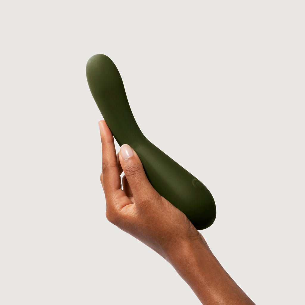 A hand holding a green personal massager against a white background.