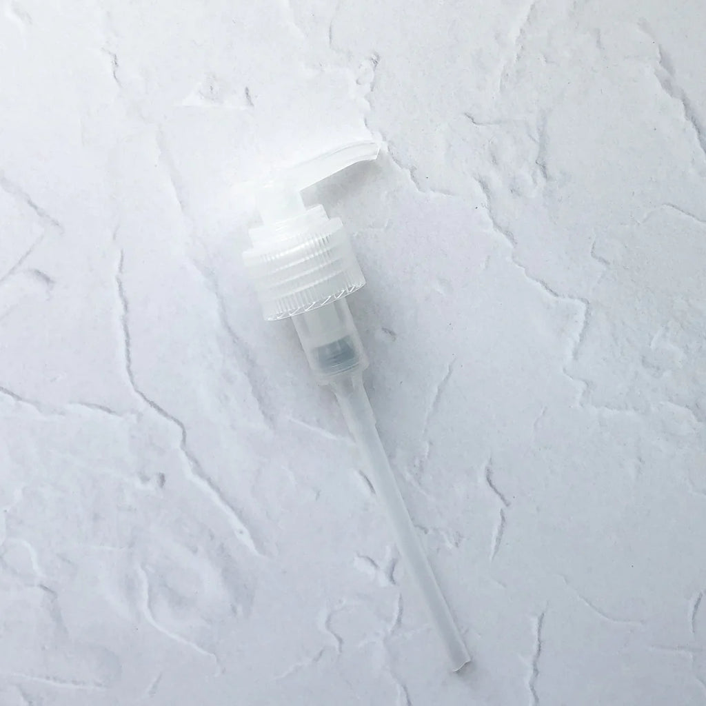 A plastic spray pump nozzle on a textured white background.