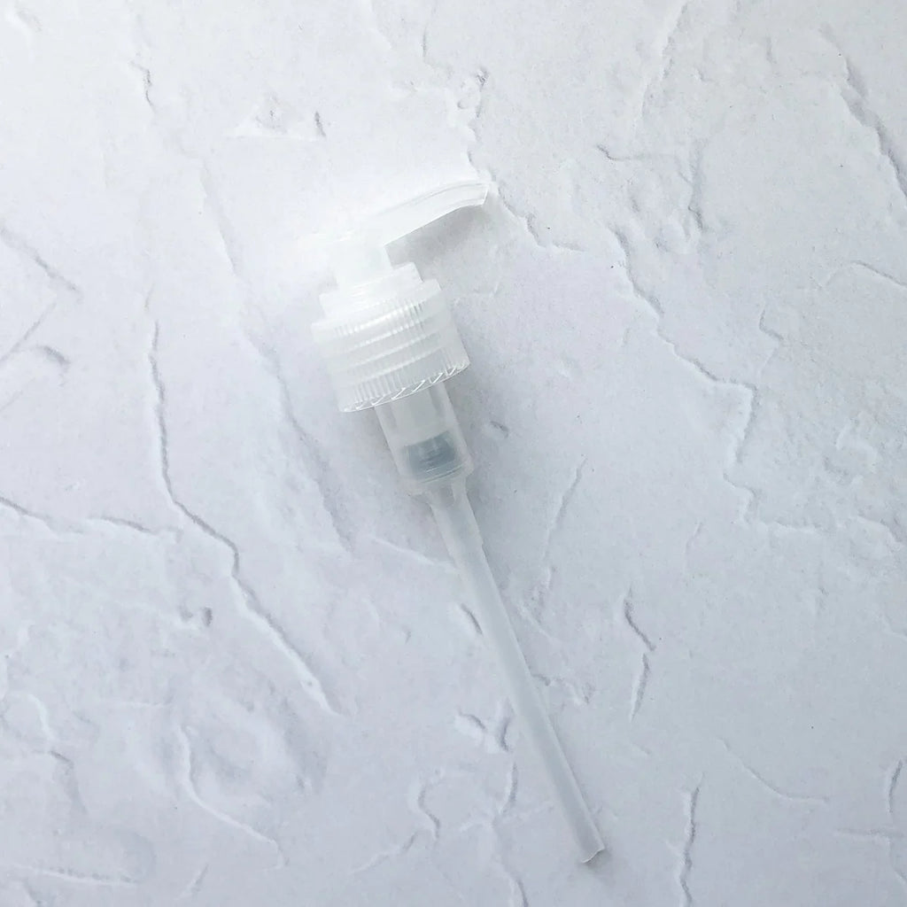 A white plastic spray pump on a textured surface.