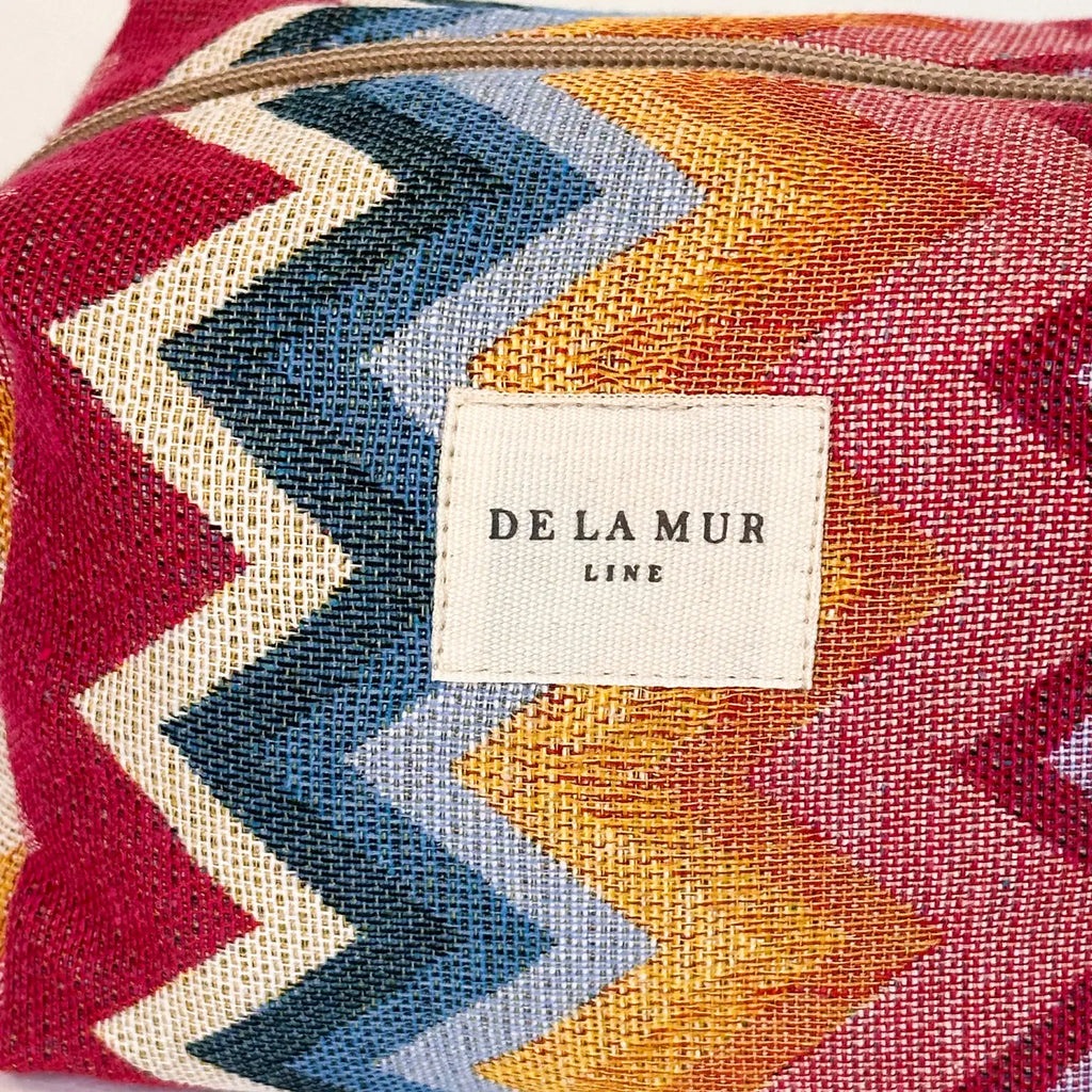 Medium toiletry bag with a zipper at the top and a side handle. Made with thick jacquard fabric with a zigzag pattern in pink and blue tones. Ideal for storing makeup, facial creams, and small bottles.
