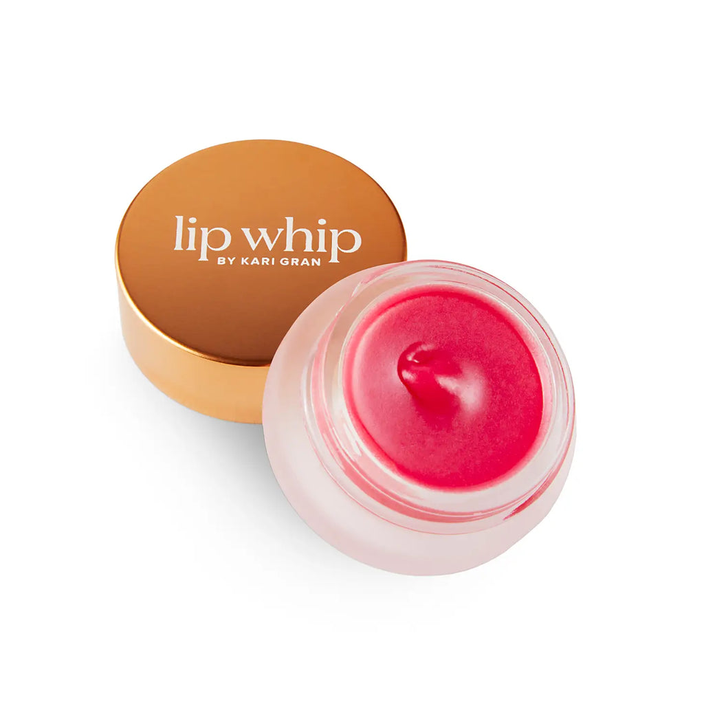 Jar of pink lip balm next to its golden lid on a white background.