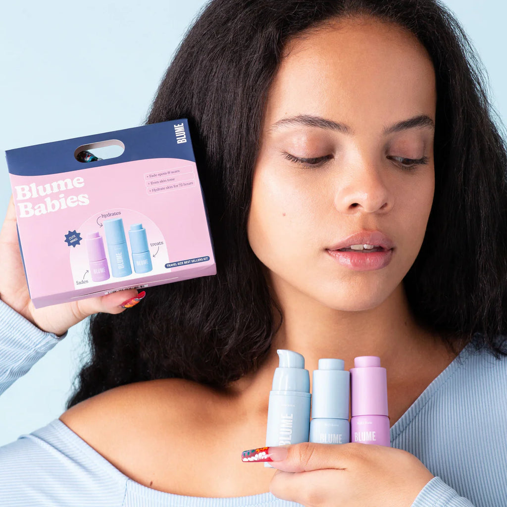 Woman holding skincare products from blume babies with a contemplative expression.