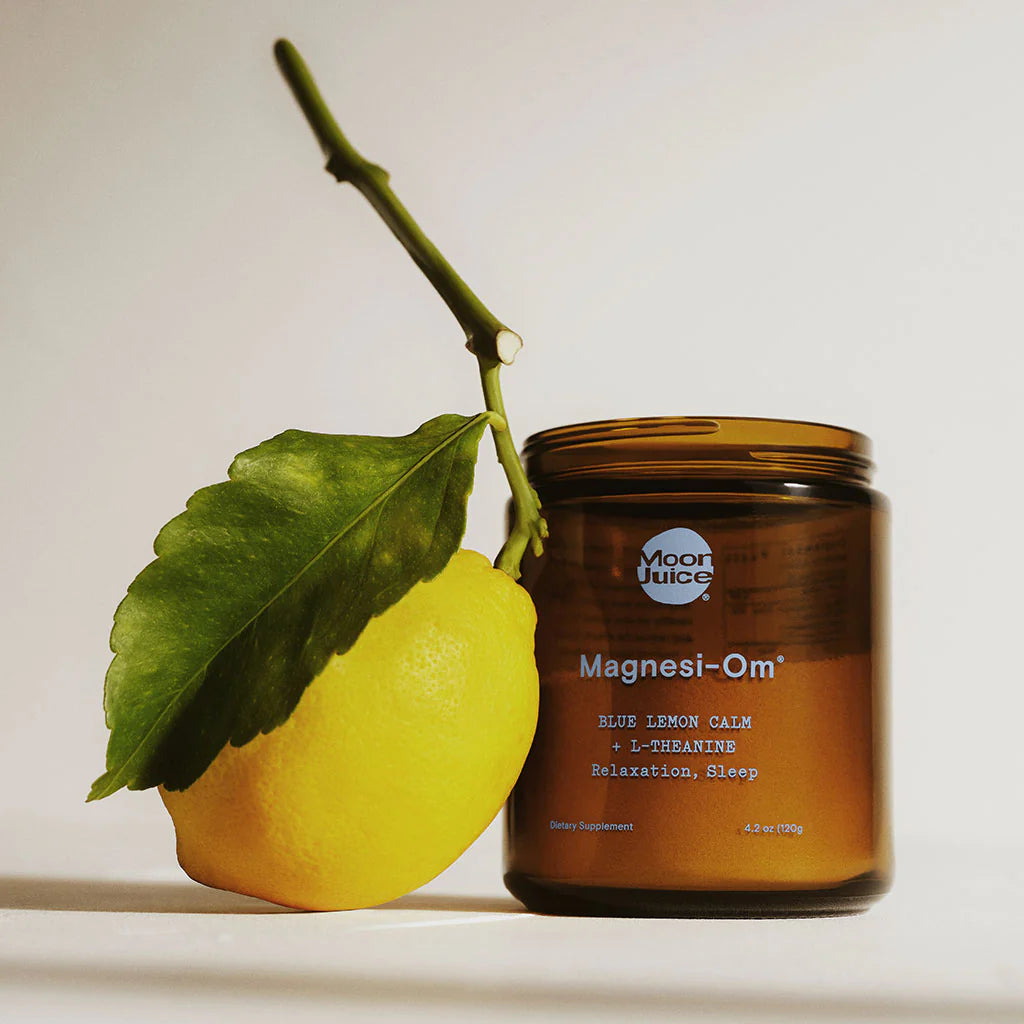 A lemon with a leaf attached rests against a jar of magnesi-om dietary supplement with the label "blue lemon calm.