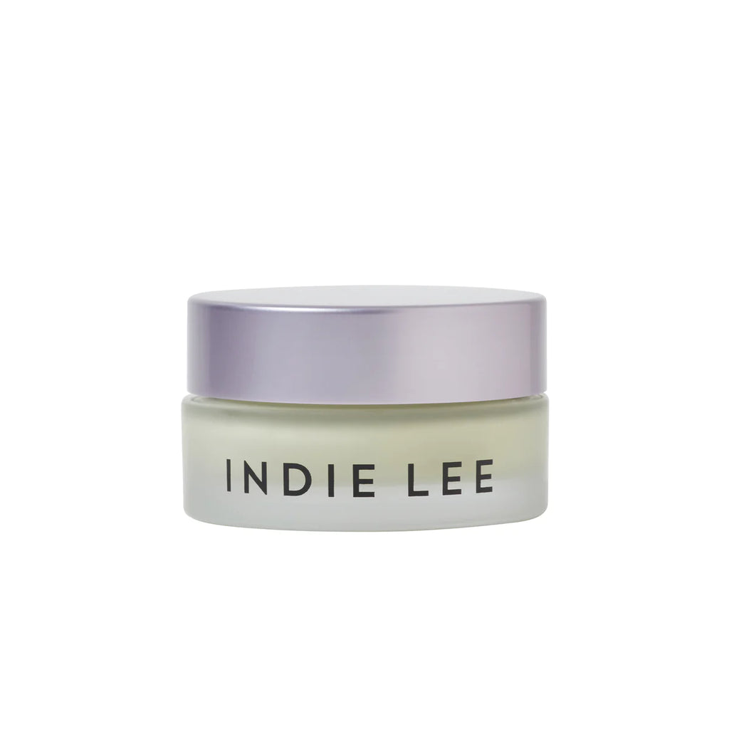 A transparent jar of Indie Lee Color Balancer with a frosted light purple lid, isolated on a white background, contains color-correcting Tiger Grass for complexion enhancement.