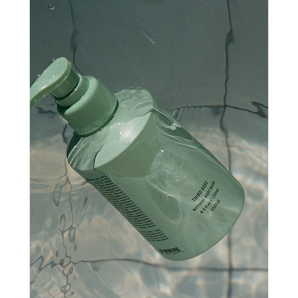 Green bottle of Third Rose body wash floating in water