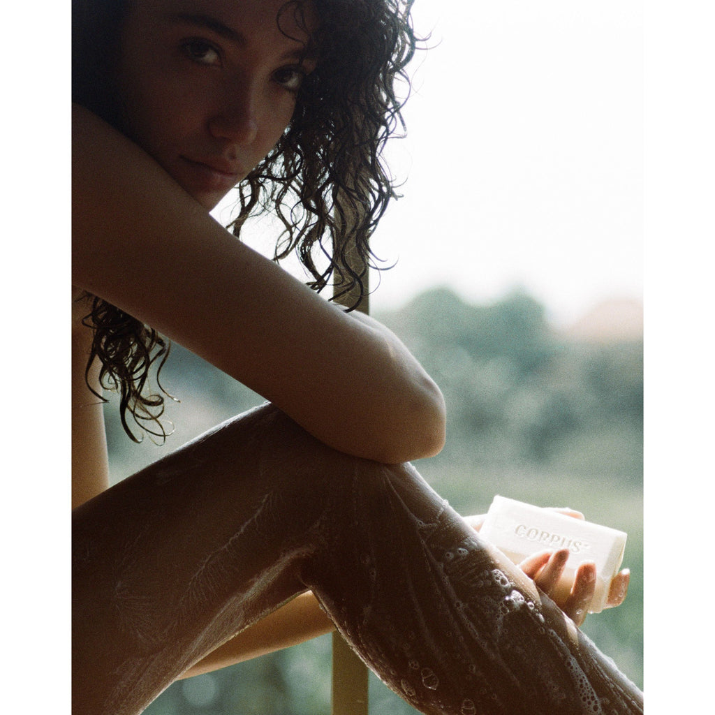 Female model with a sudsy leg holding a bar of corpus soap