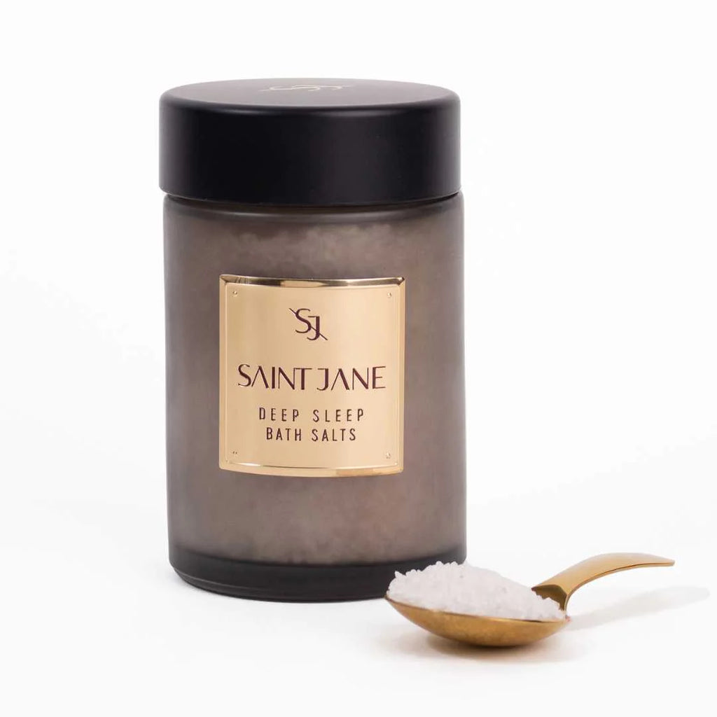 Container of saint jane deep sleep bath salts with a spoonful of product next to it against a white background.