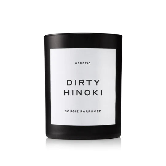 A black candle labeled "heretic dirty hinoki bougie parfumee" against a white background.