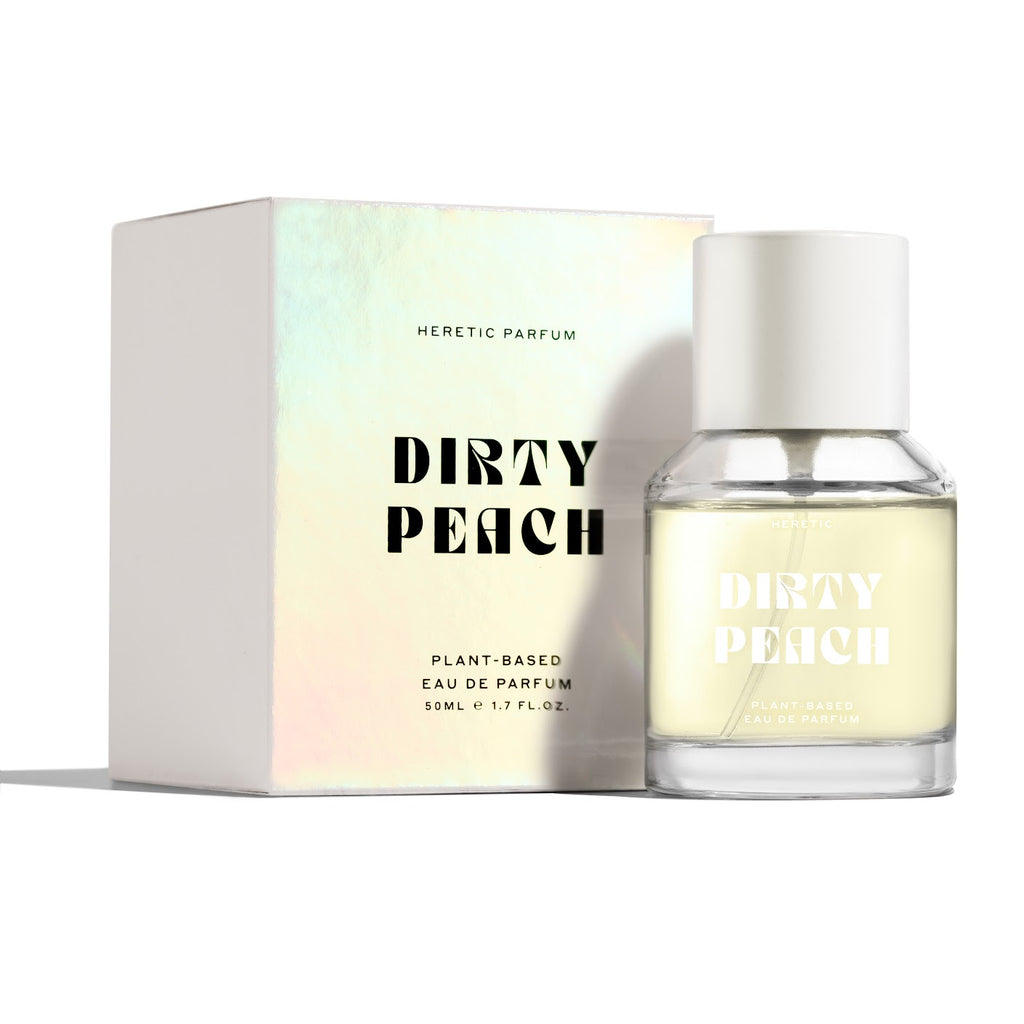 A bottle of heretic perfume's "dirty peach" eau de parfum next to its box on a white background.