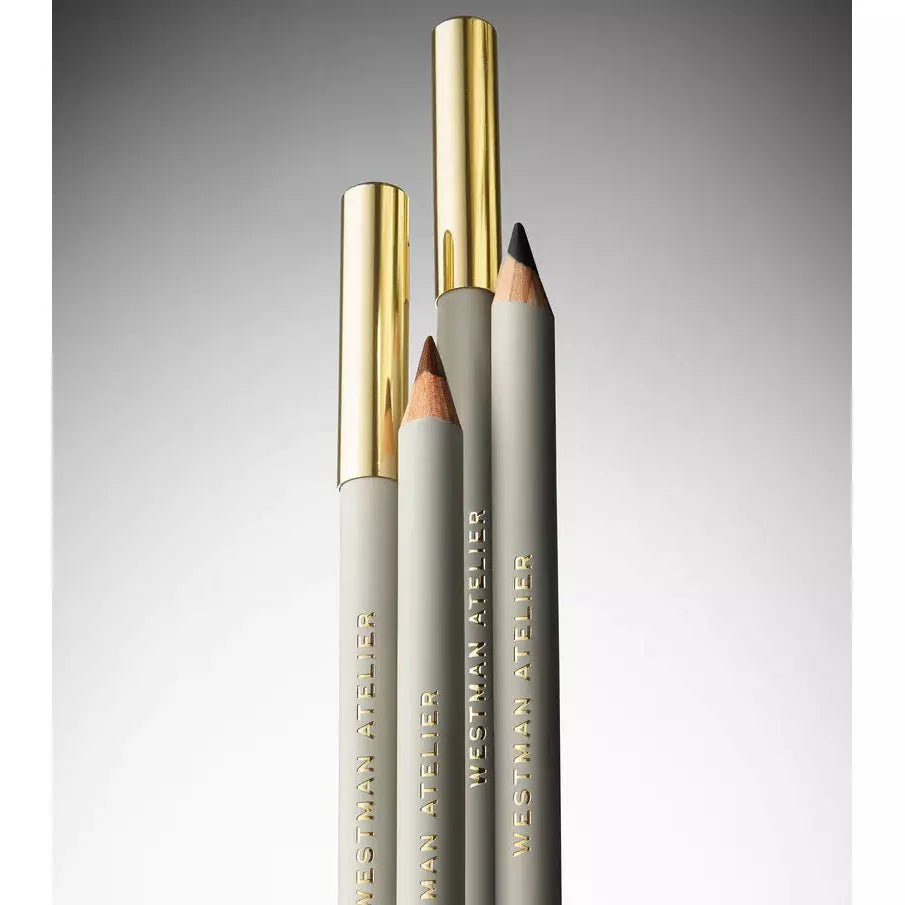 Three elegant cosmetic pencils with golden caps on a gradient background.
