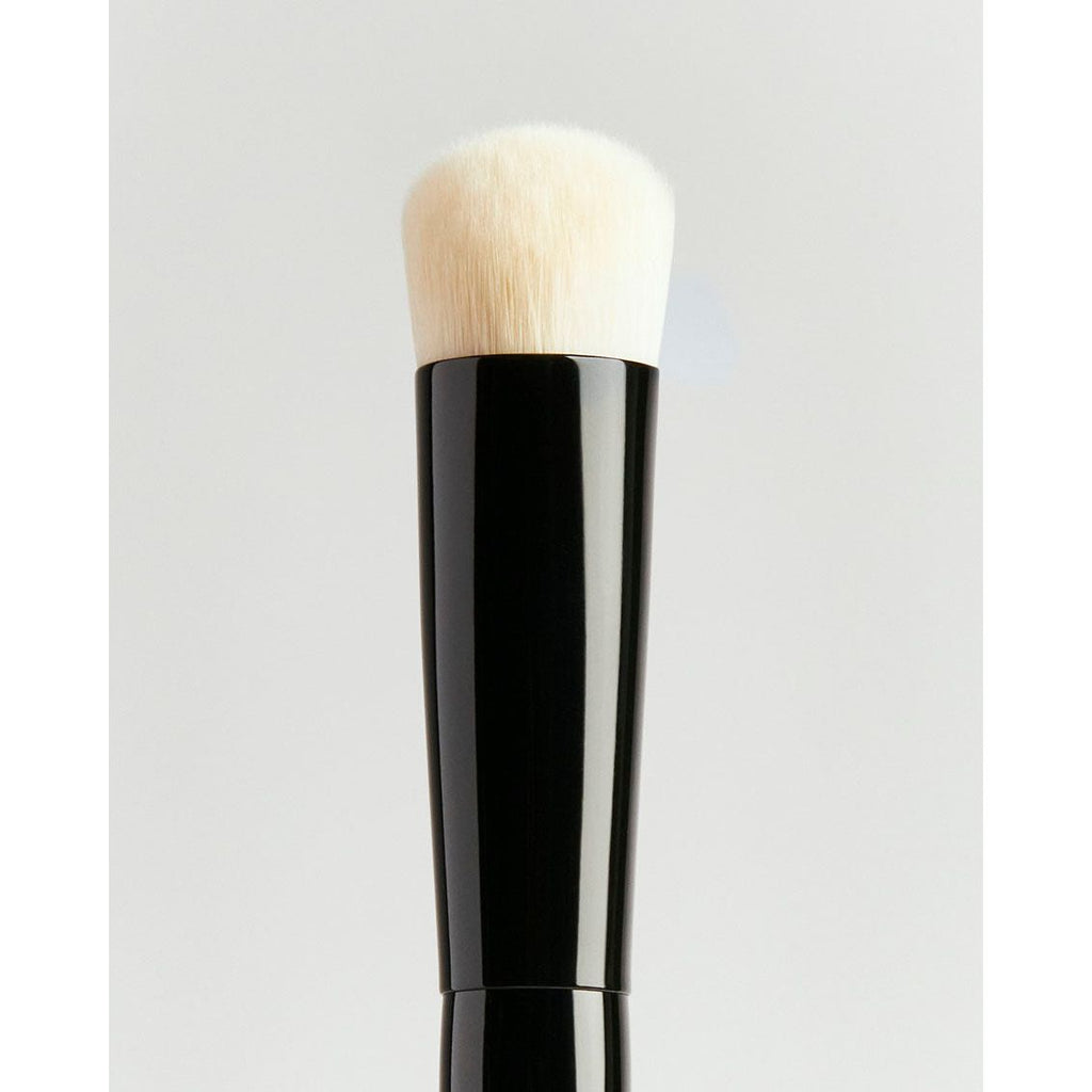 Close-up of a makeup brush against a neutral background.