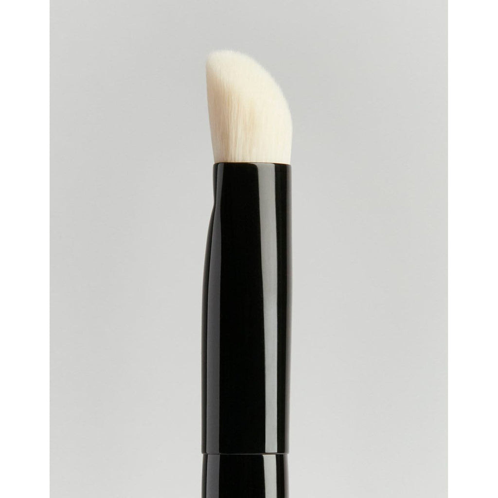 Makeup brush with black handle on a neutral background.
