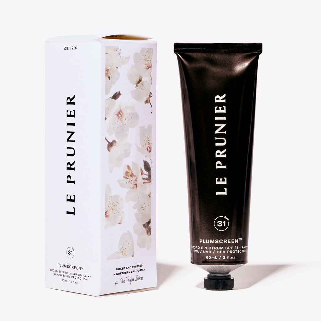 A tube of le prunier plum beauty oil and its packaging, featuring floral design elements.