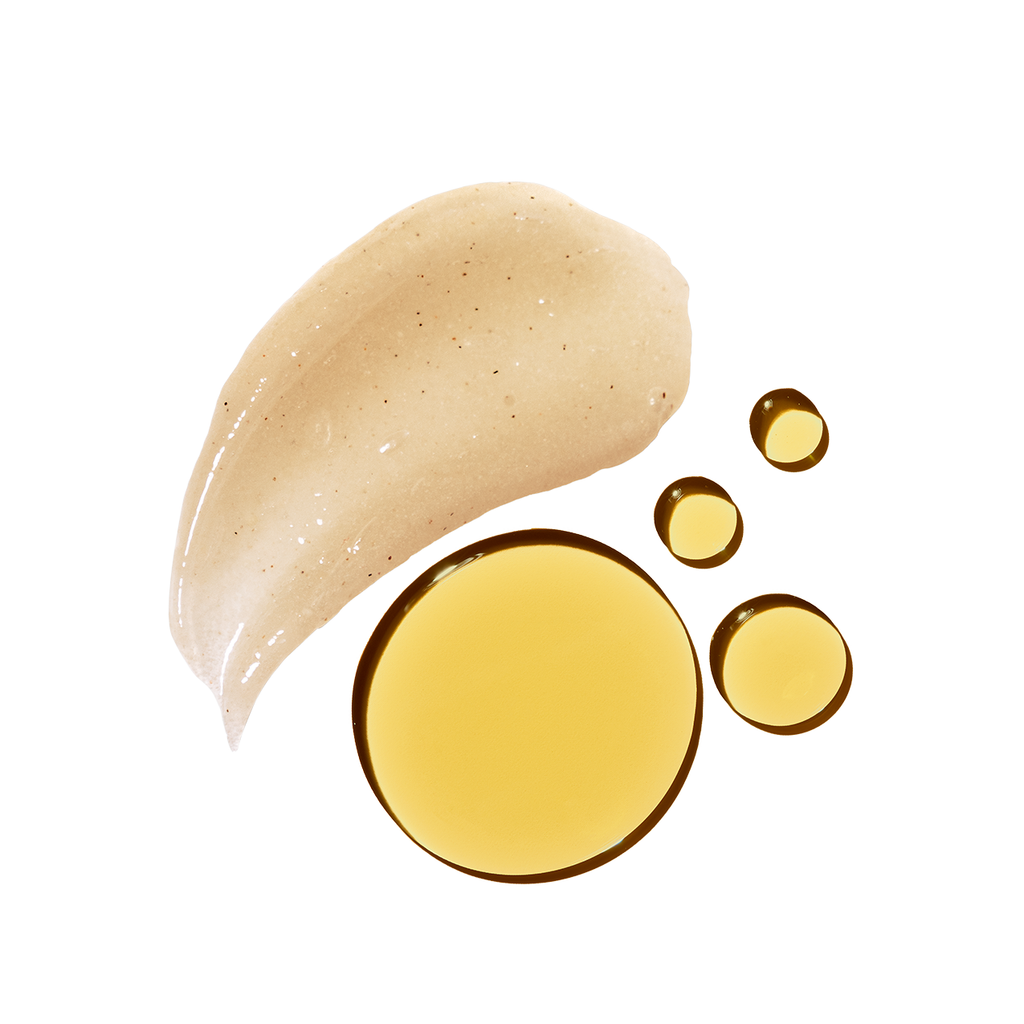 A smudge of exfoliating scrub next to droplets of a golden fluid, possibly a skincare oil, isolated on a white background.