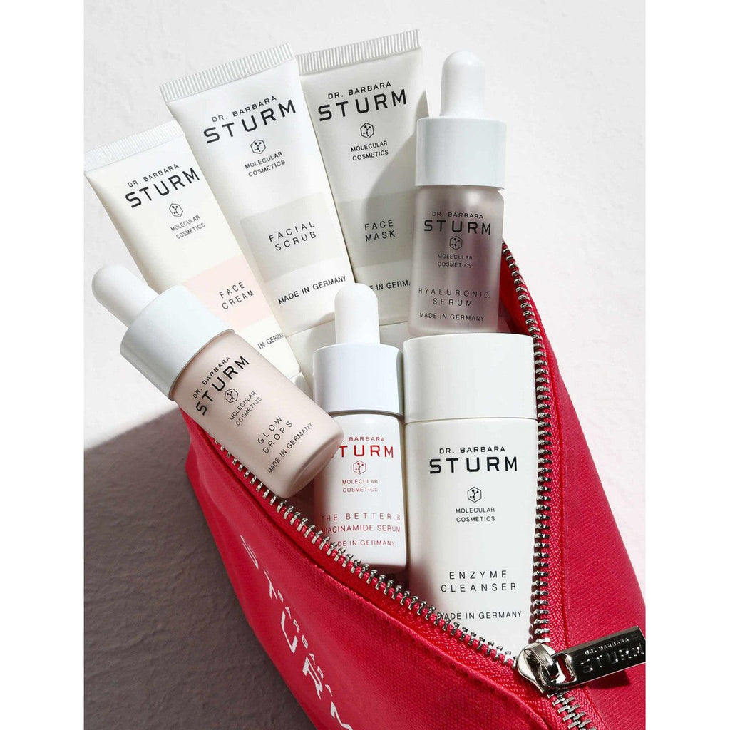 A collection of dr. barbara sturm skincare products in a red cosmetic bag.