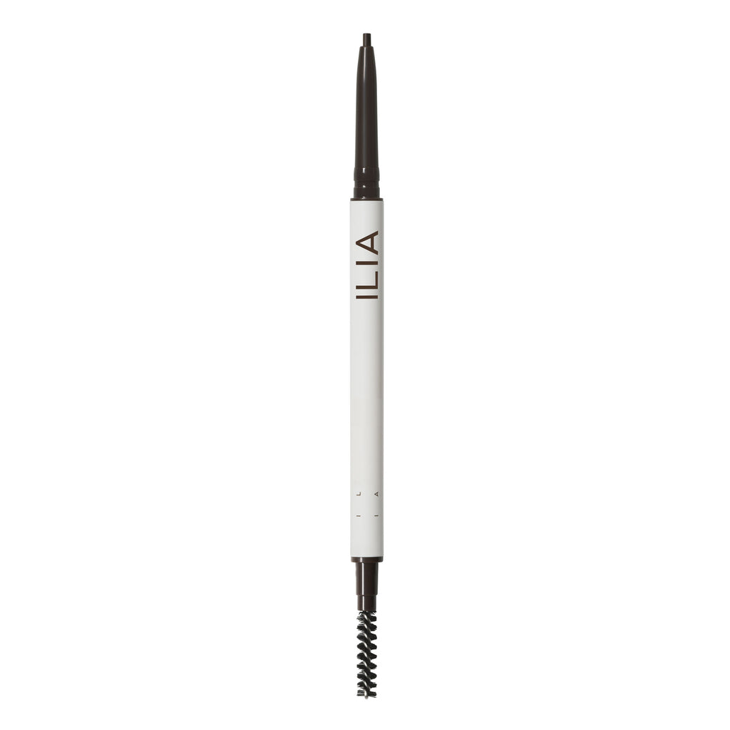 A close-up of an ilia brand eyebrow pencil with a spoolie brush on one end.