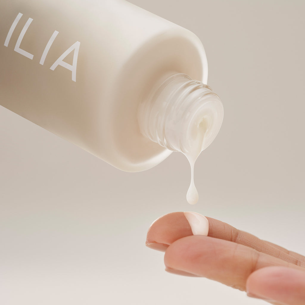 Dispensing a drop of lotion from a bottle onto a fingertip.