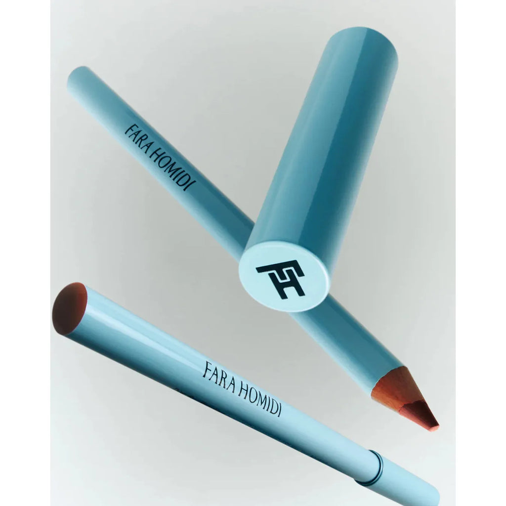 Two lip pencils positioned in a cross shape with the caps off, revealing the pointed makeup tip on one.