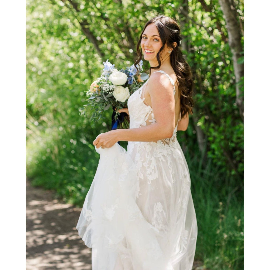 A smiling bride in a white dress holding a bouquet of flowers.