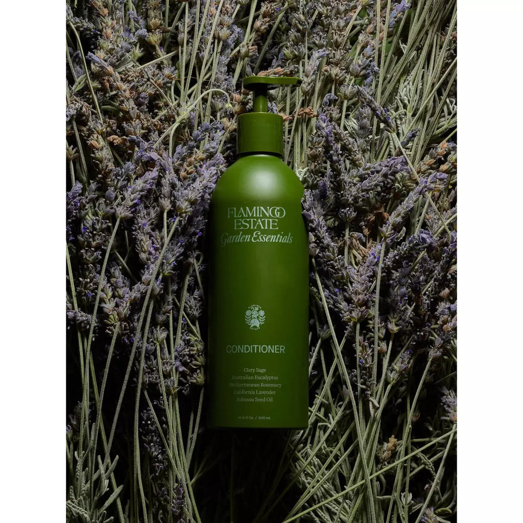 Green conditioner bottle nestled in a bed of lavender flowers.
