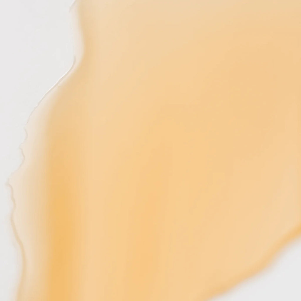 Close-up of a fluid orange substance with a smooth, creamy texture on a white background.