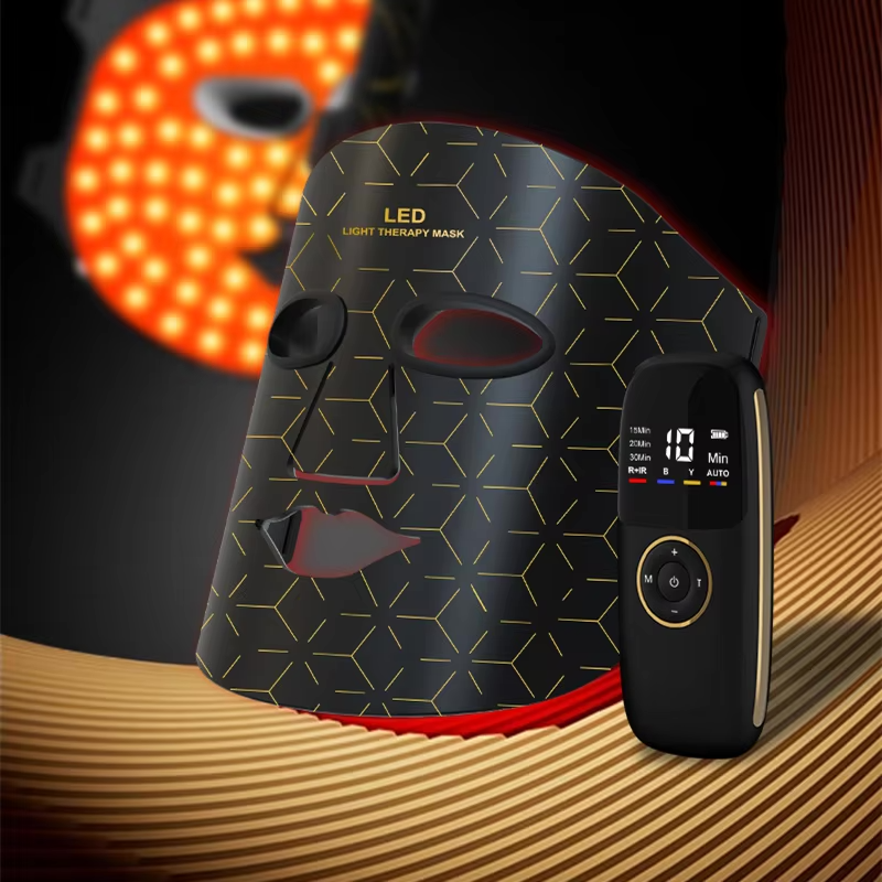 The Wren and Wild LED Beauty Mask + Neck Device, featuring a sleek black design with geometric patterns and full spectrum LED technology, is displayed on a textured surface beside its handheld remote control. An orange variant of the LED beauty mask can be seen in the background.