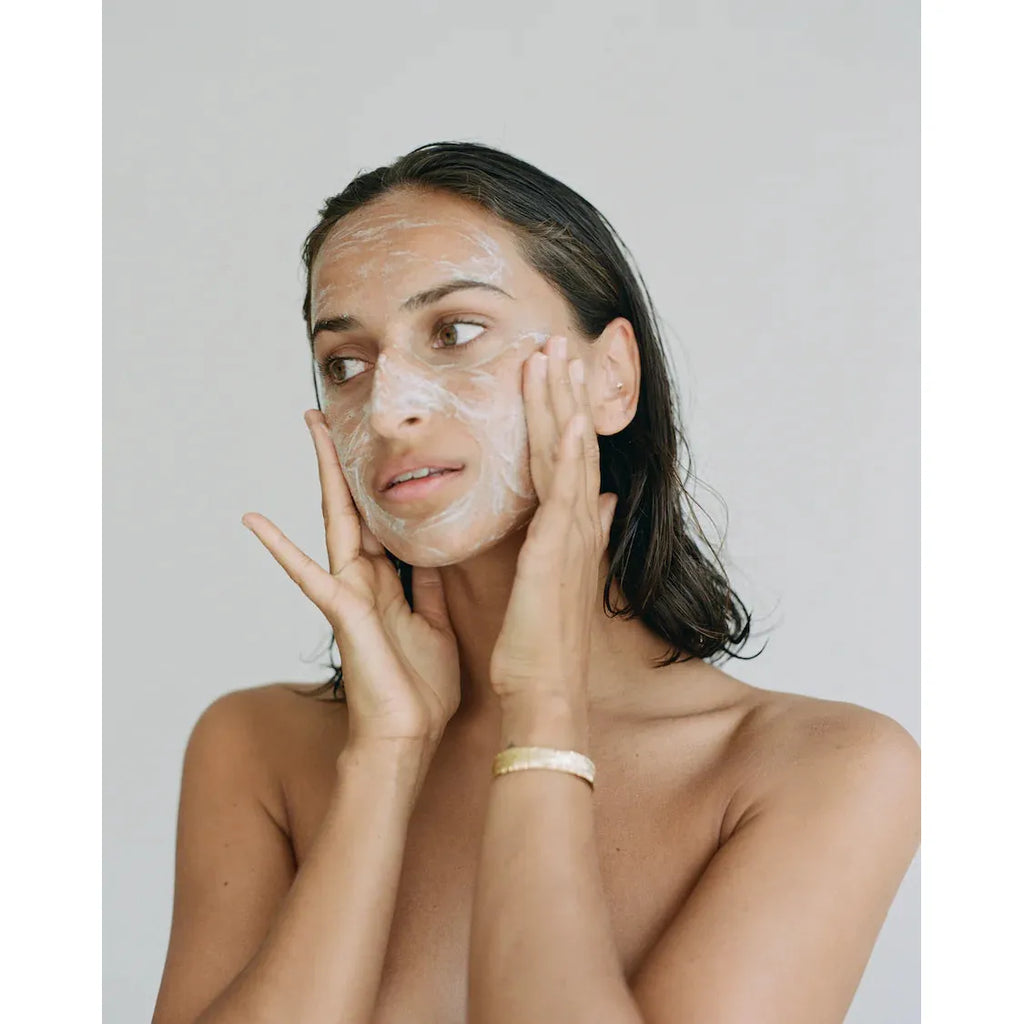 Woman applying facial skincare mask.