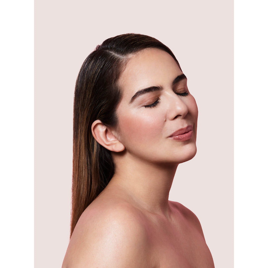 Woman with closed eyes and bare shoulders on a neutral background.