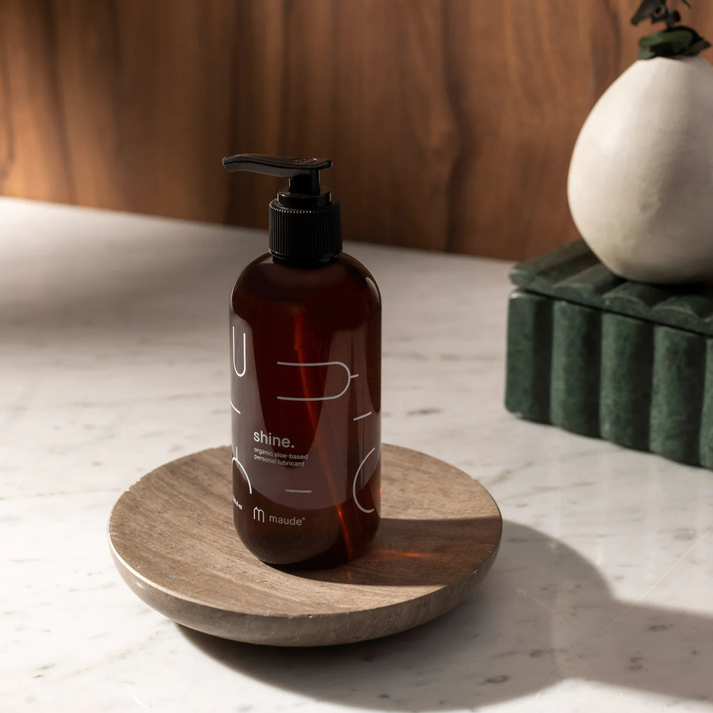 Amber-hued soap dispenser on a wooden dish against a marble countertop.