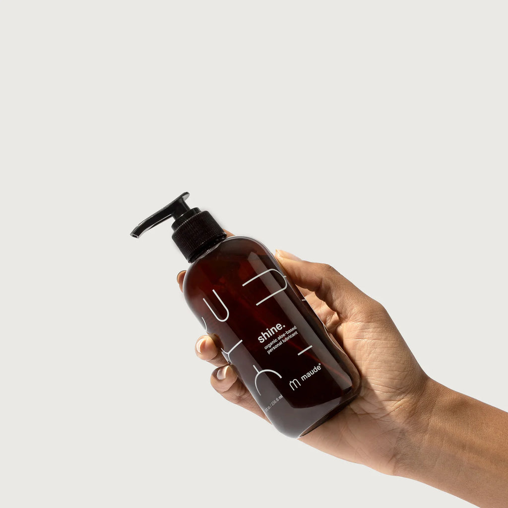 A hand holding a bottle of liquid product with a pump dispenser against a white background.
