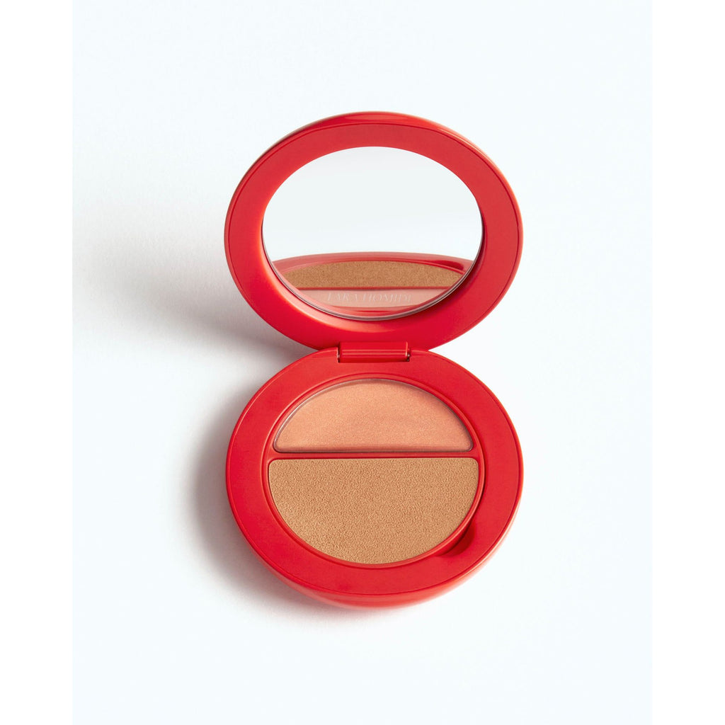 A compact with an open lid revealing a mirror and a split pan of highlighter and bronzer makeup.