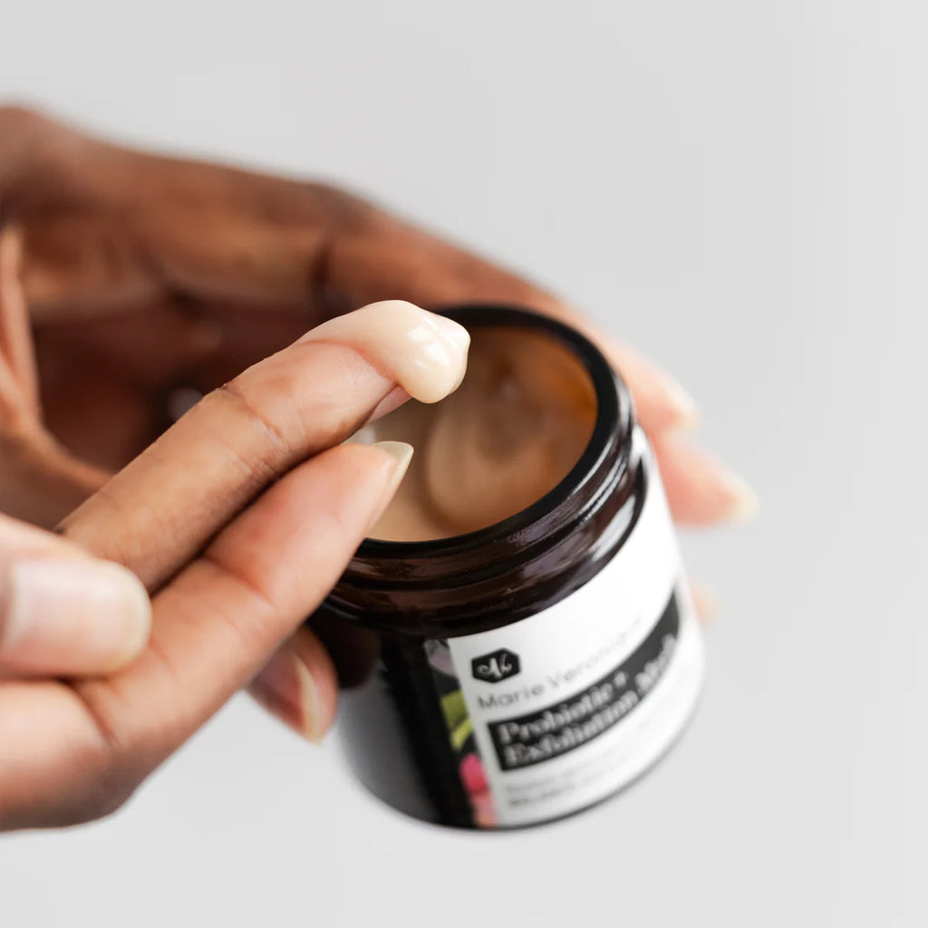 Person dipping finger into a jar of cosmetic cream.