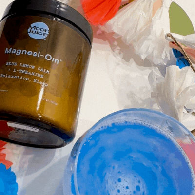 A jar of magnesi-om supplement beside a blue drink and scattered tissues.