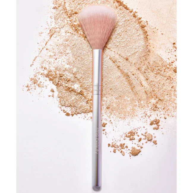 Makeup brush with scattered powder on a clean surface.