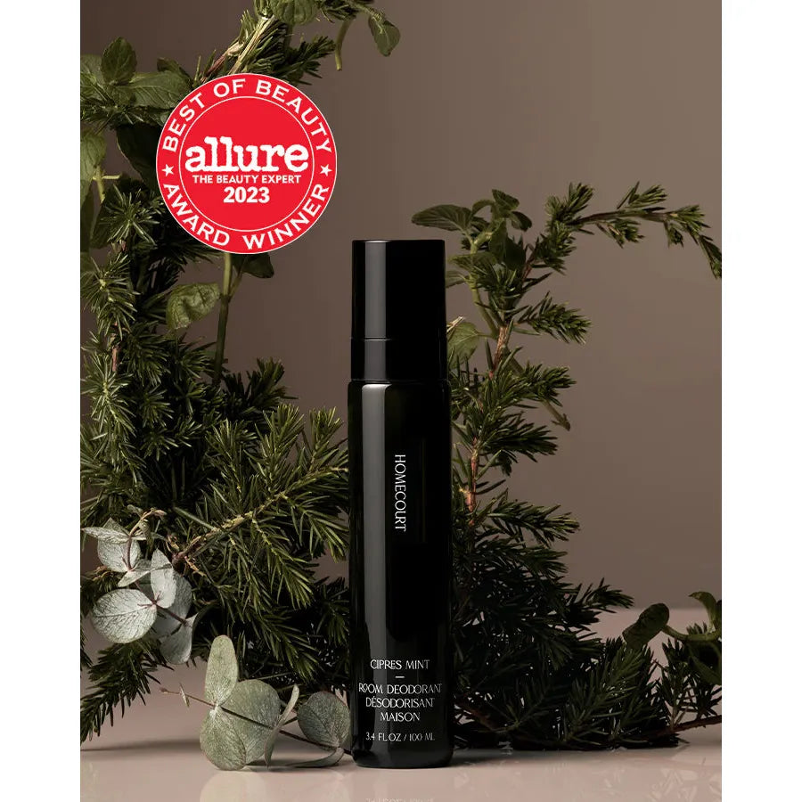 Room deodorant spray bottle with a mint fragrance, positioned among green plants with an allure best of beauty award sticker.