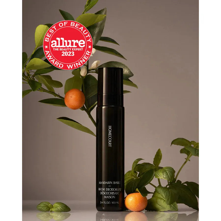 Homecourt room deodorant by Korres featuring an Allure 2023 award badge, set against a backdrop of green leaves and small orange fruits.