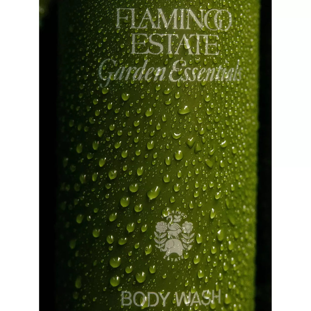 Close-up of a green body wash bottle with water droplets on it.