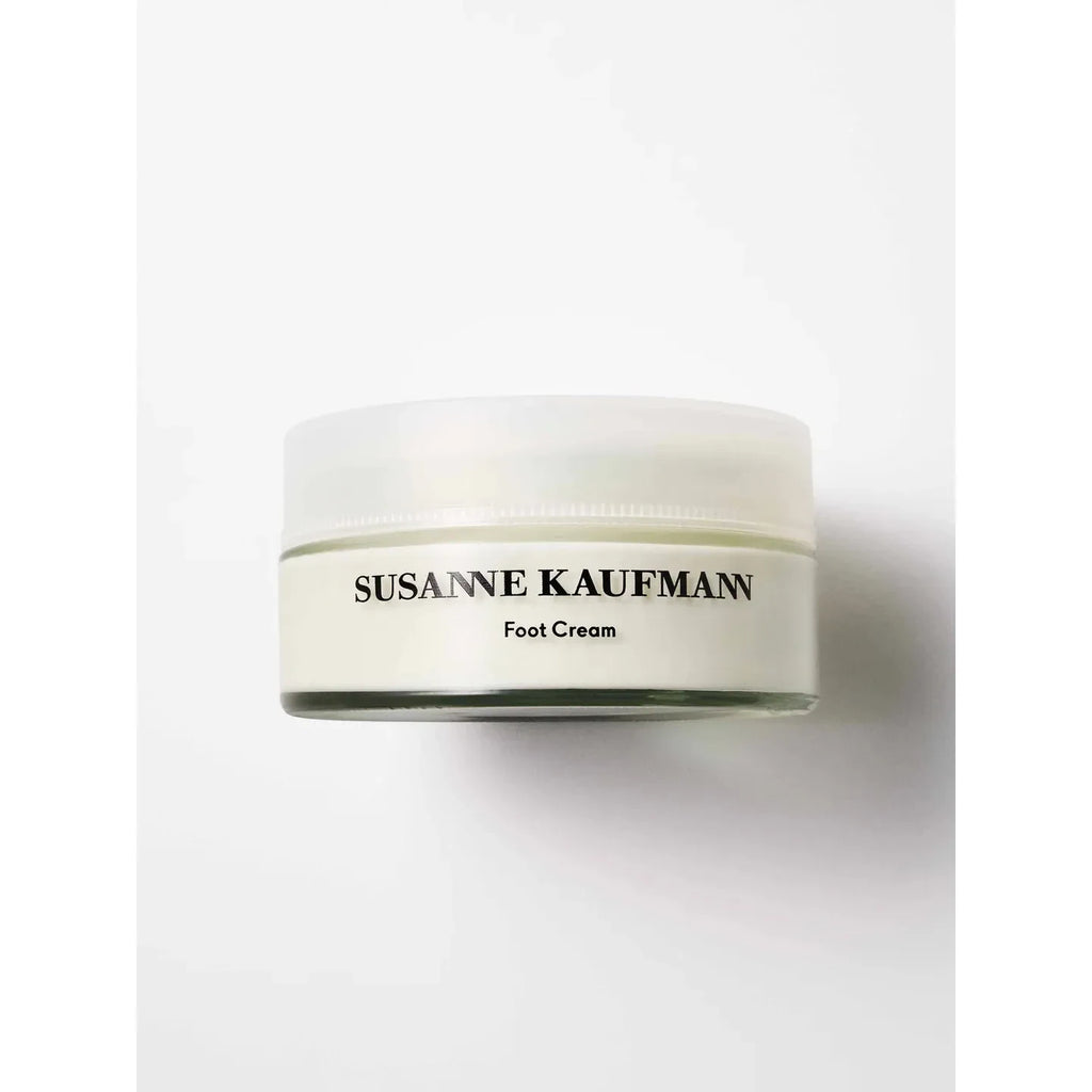 A white jar labeled "Susanne Kaufmann Foot Cream" sits on a plain white background, highlighting its nourishing blend designed to rejuvenate tired feet.