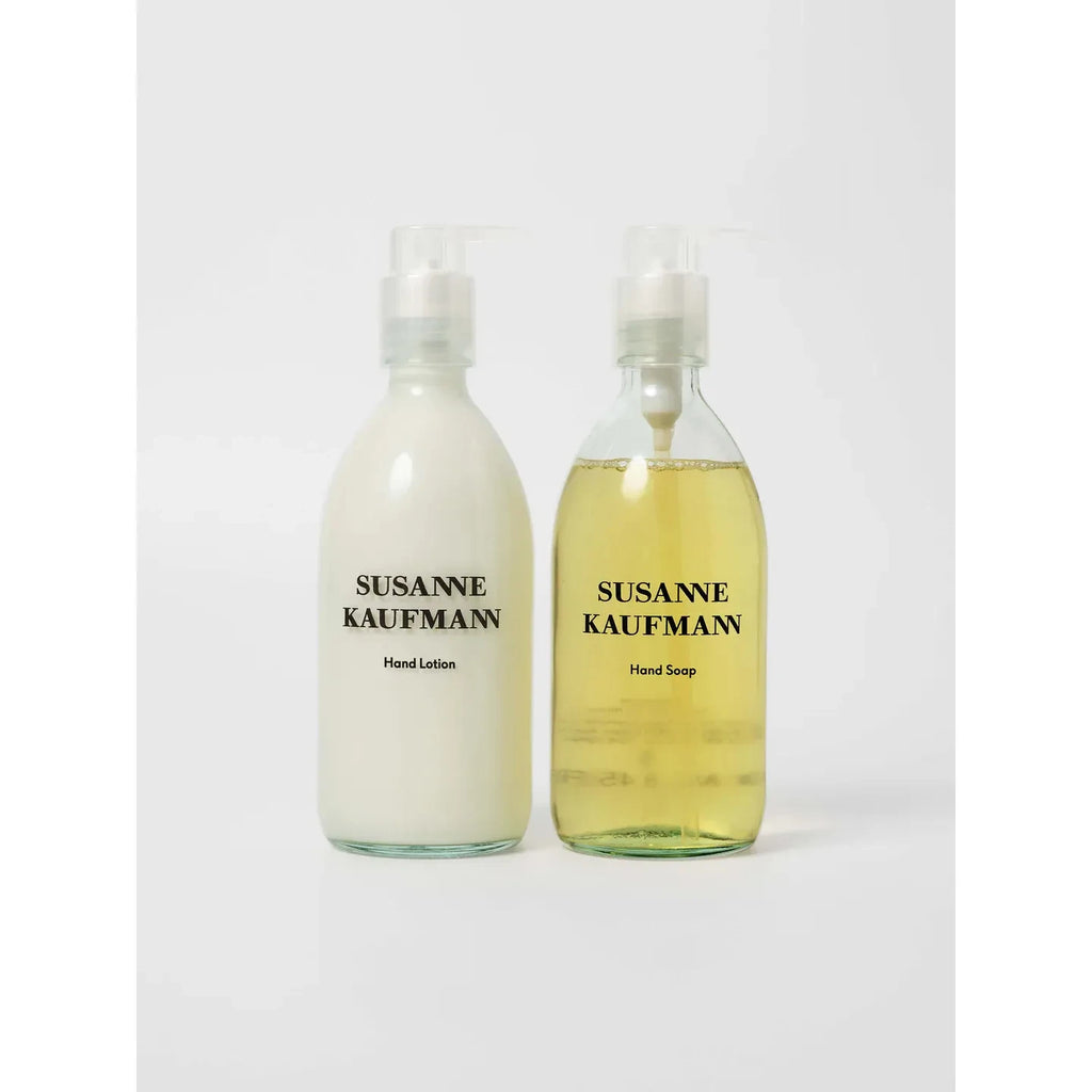 The Susanne Kaufmann Hand Soap & Hand Lotion Set includes two clear pump bottles. One bottle contains moisturizing hand lotion filled with white lotion, while the other holds hand soap filled with yellow liquid.