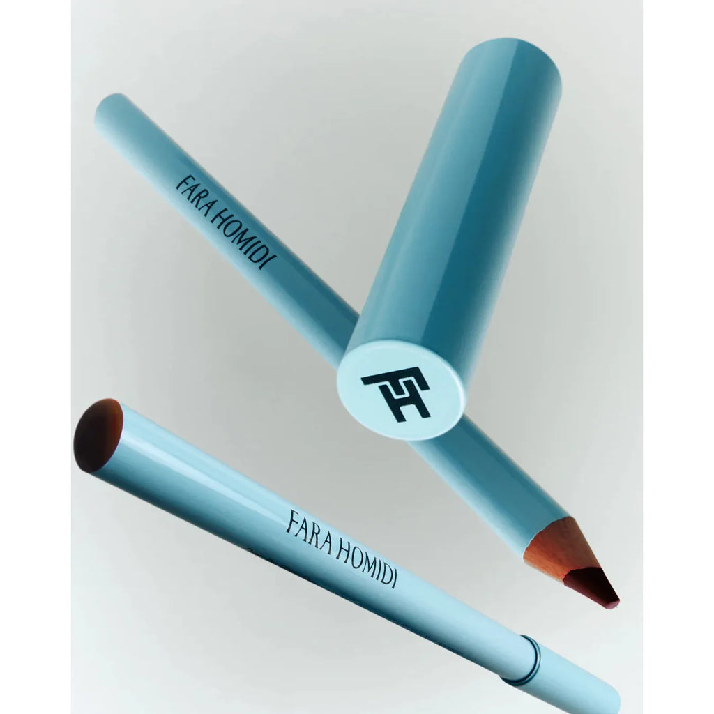 Blue cosmetic pencil with cap off, revealing color tip, against a light background.