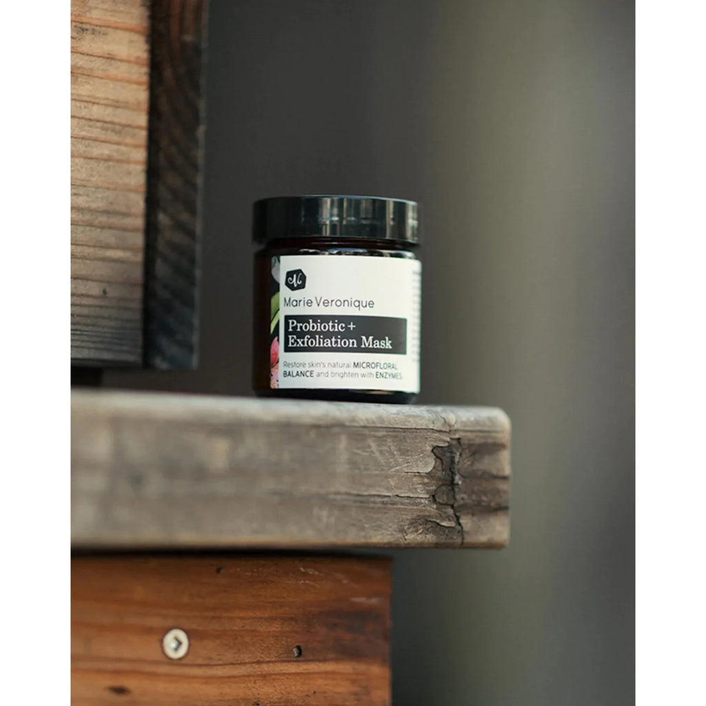 A jar of marie veronique probiotic+ exfoliation mask placed on a wooden ledge.