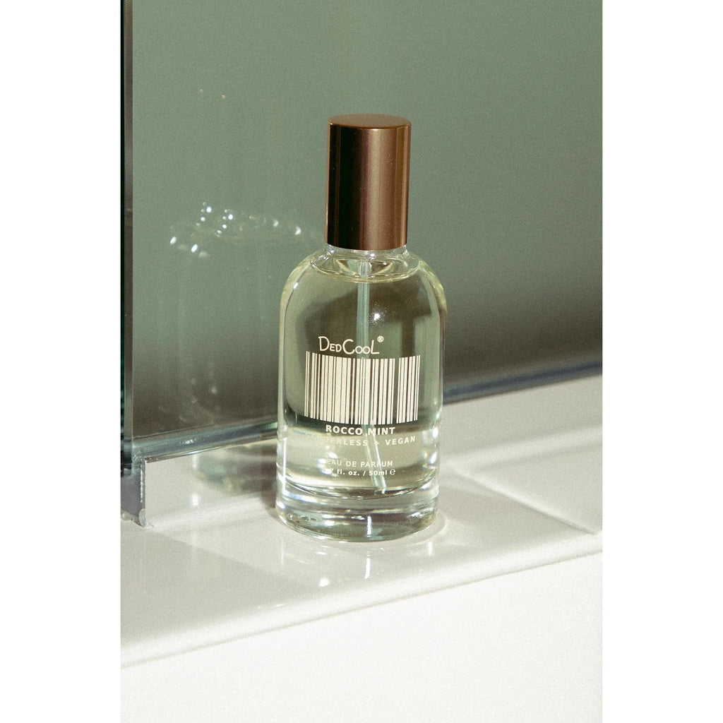 A bottle of dedcool fragrance perched on a glass surface.