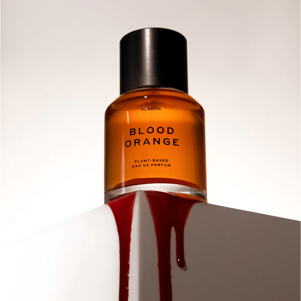 Bottle of "blood orange" plant-based eau de parfum with liquid spilling out to resemble its namesake.