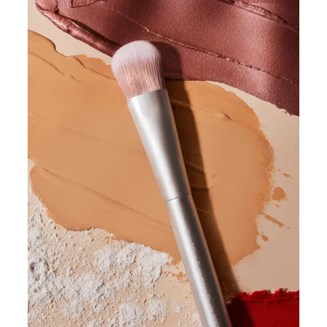 Makeup brush resting on a palette of various shades of foundation.