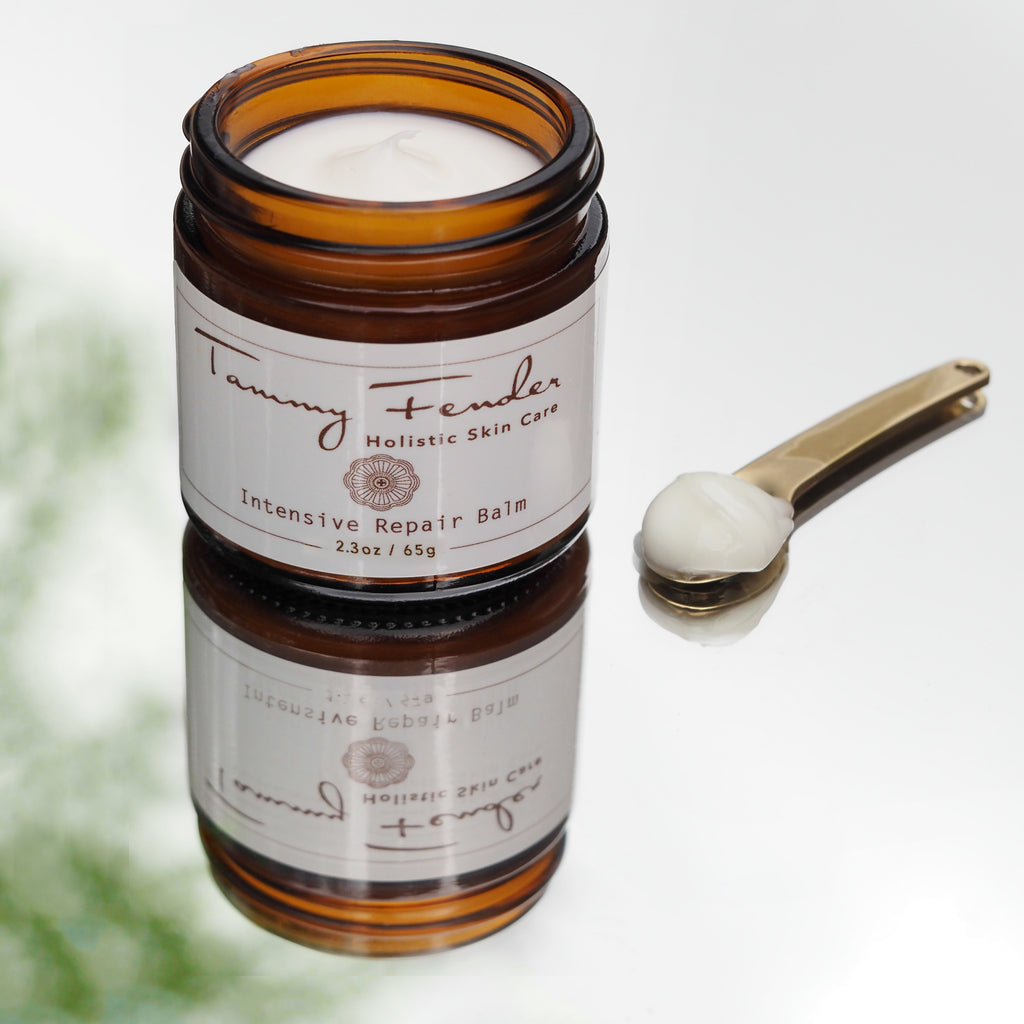 A jar of holistic skin care intensive repair balm with a small scoop containing some of the product beside it.